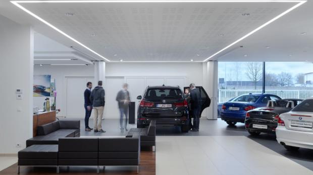 Die Beleuchtung des BMW Autohauses unterlag strengen Gestaltungsvorgaben. Hier die Inszenierung der Neuwagenübergabe mit einem Lichtrahmen aus SLOTLIGHT II Eckverbindern. Foto: Zumtobel
